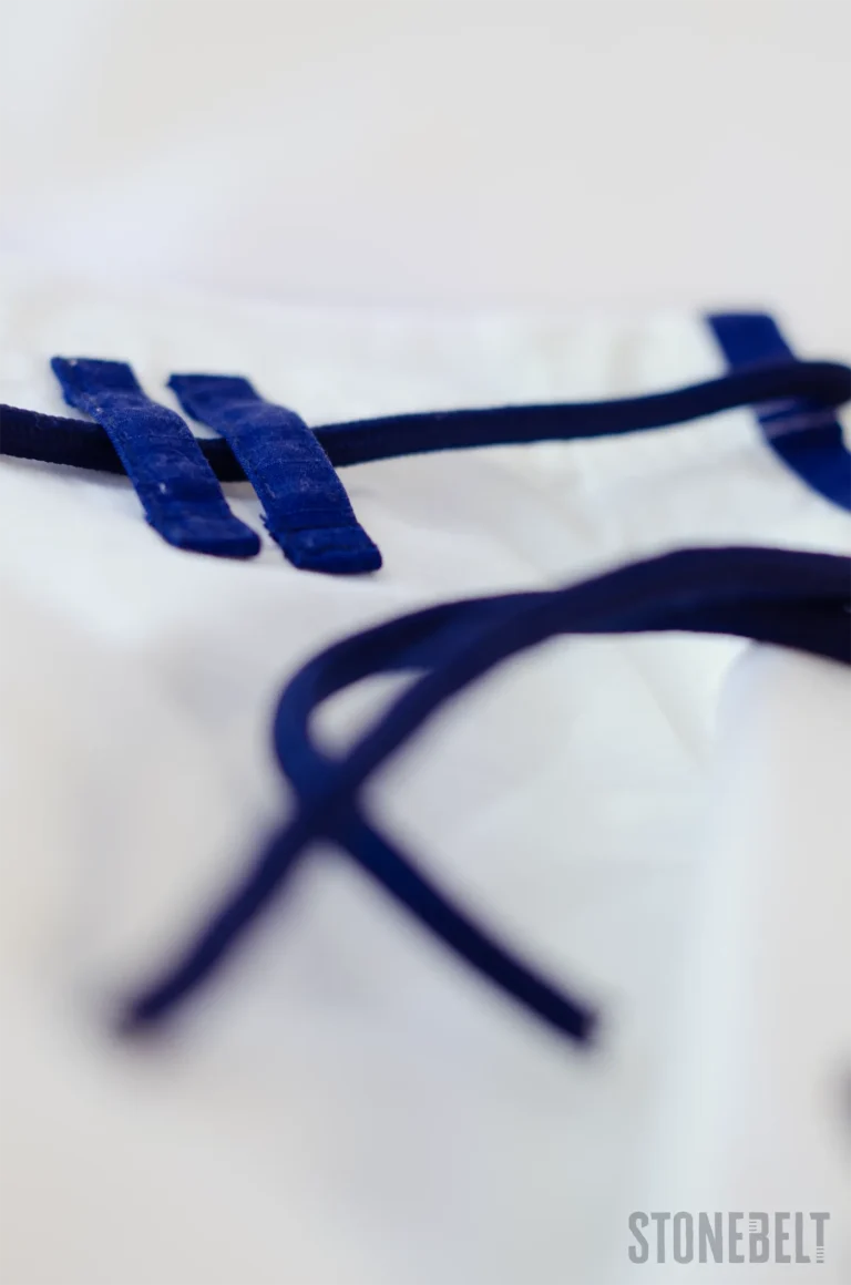 Macro close-up of Stonebelt Heritage BJJ gi ripstop pants showing reinforced navy drawstring loops and durable cord construction