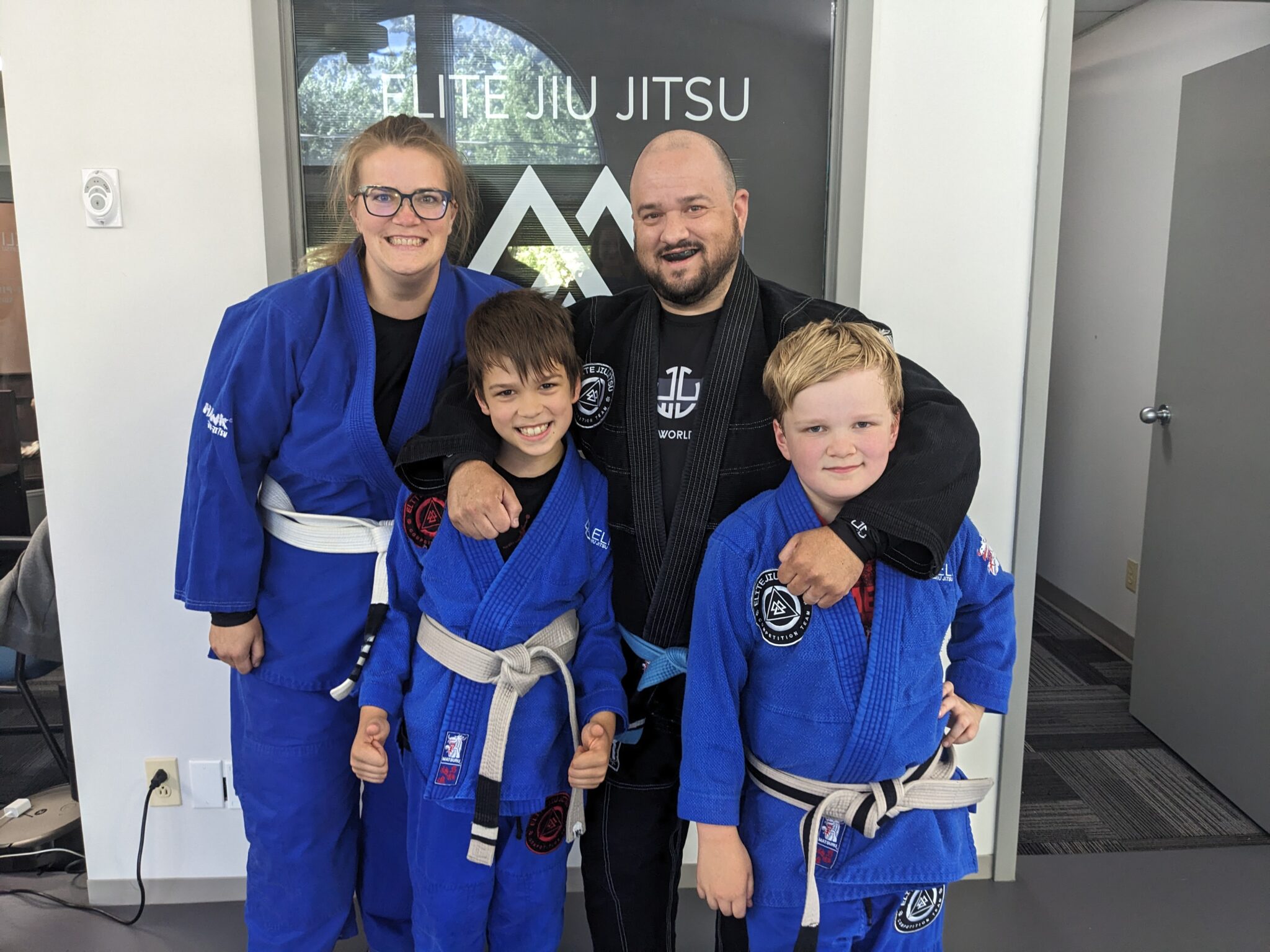 Stonebelt founder with family in blue jiu-jitsu gis at the academy.