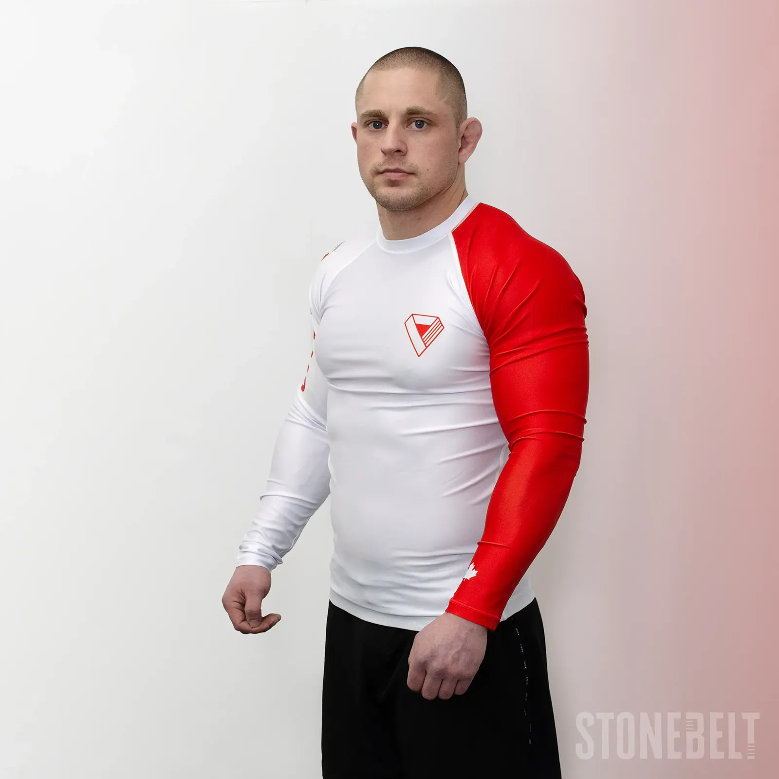 Three-quarter left view of Stonebelt Heritage long sleeve rashguard showing red sleeve, chest logo, and compression fit