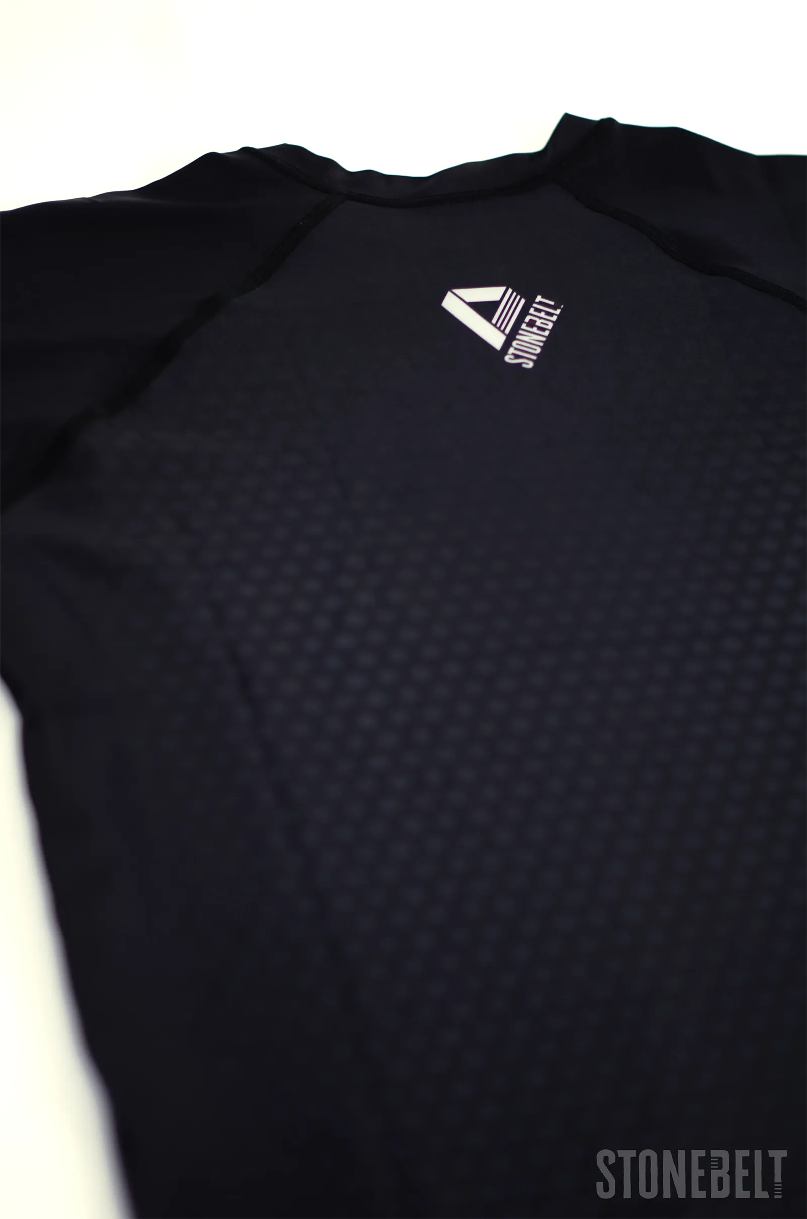 Back detail of Stonebelt Legion rashguard showing Stonebelt logo on black sublimated maple leaf pattern fabric