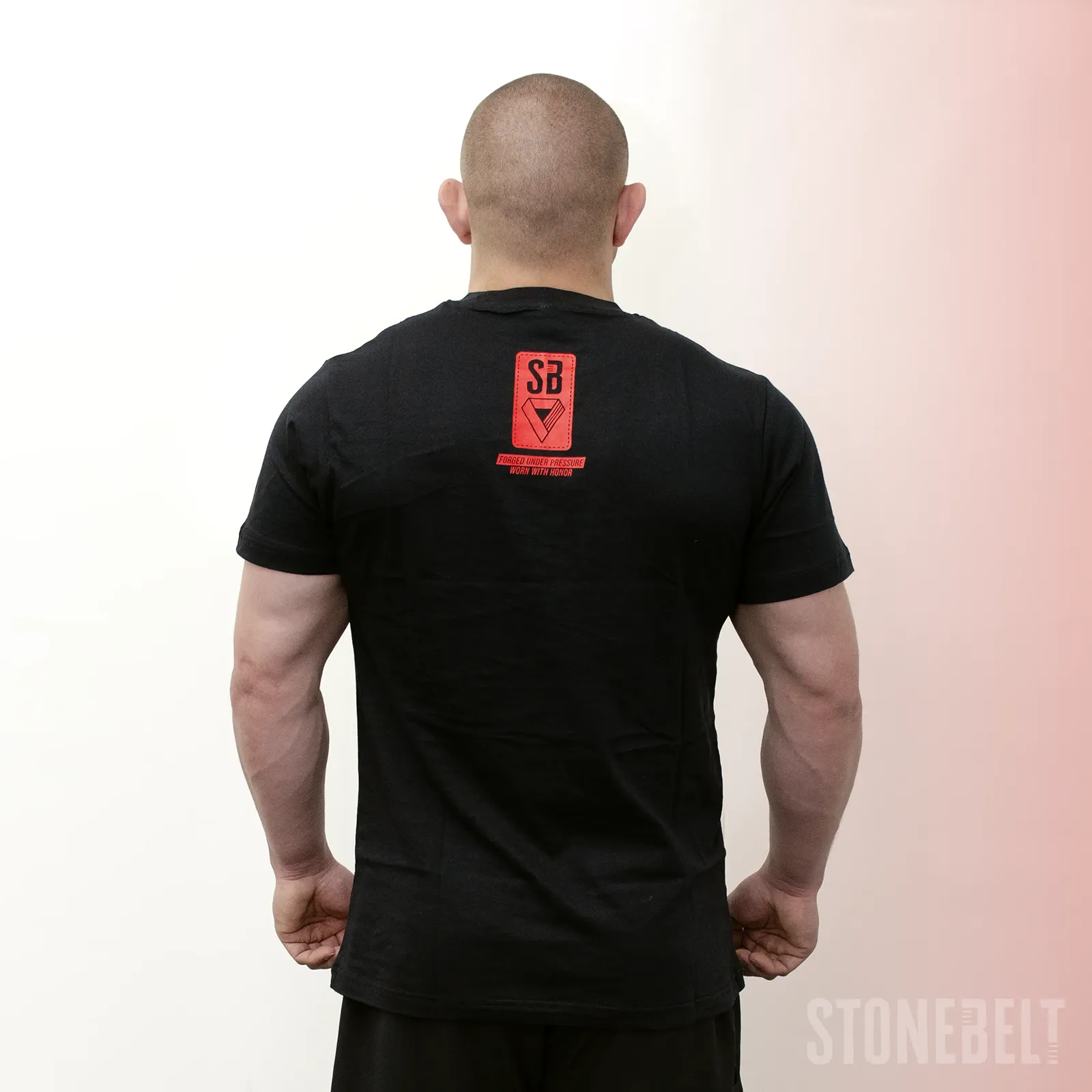 Back view of Stonebelt Classic Logo Tee in black showing red SB logo badge with Forged Under Pressure Worn With Honor tagline