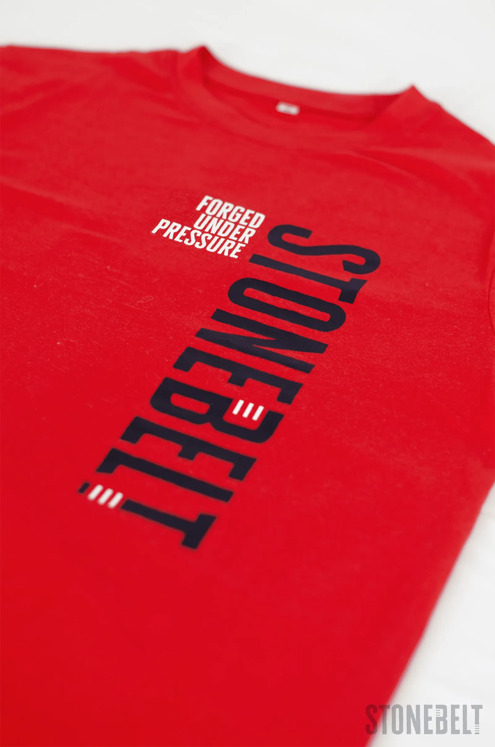 Close-up of Stonebelt Classic Logo Tee in red showing full vertical Stonebelt logo and Forged Under Pressure detail