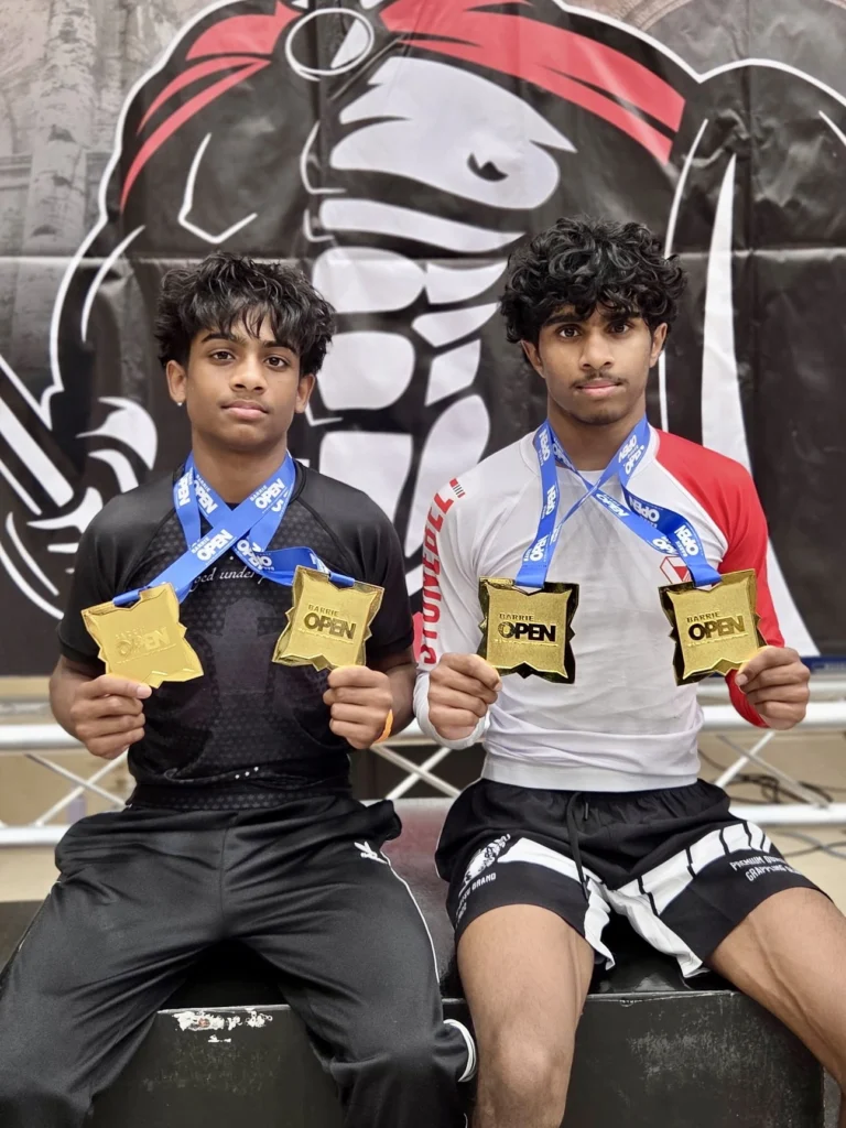Two Brazilian Jiu-Jitsu athletes wearing Stonebelt rashguards with medals