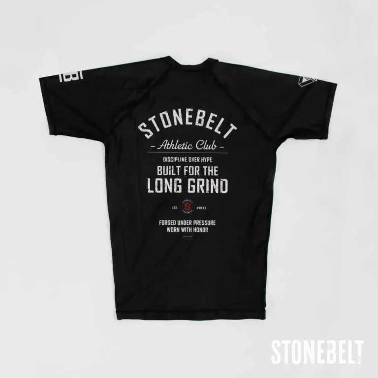 Stonebelt Athletic Club short sleeve BJJ rashguard in black, flat back view with Built for the Long Grind graphic