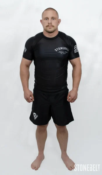 Model in Stonebelt Athletic Club black rashguard and black Heritage grappling shorts, front view