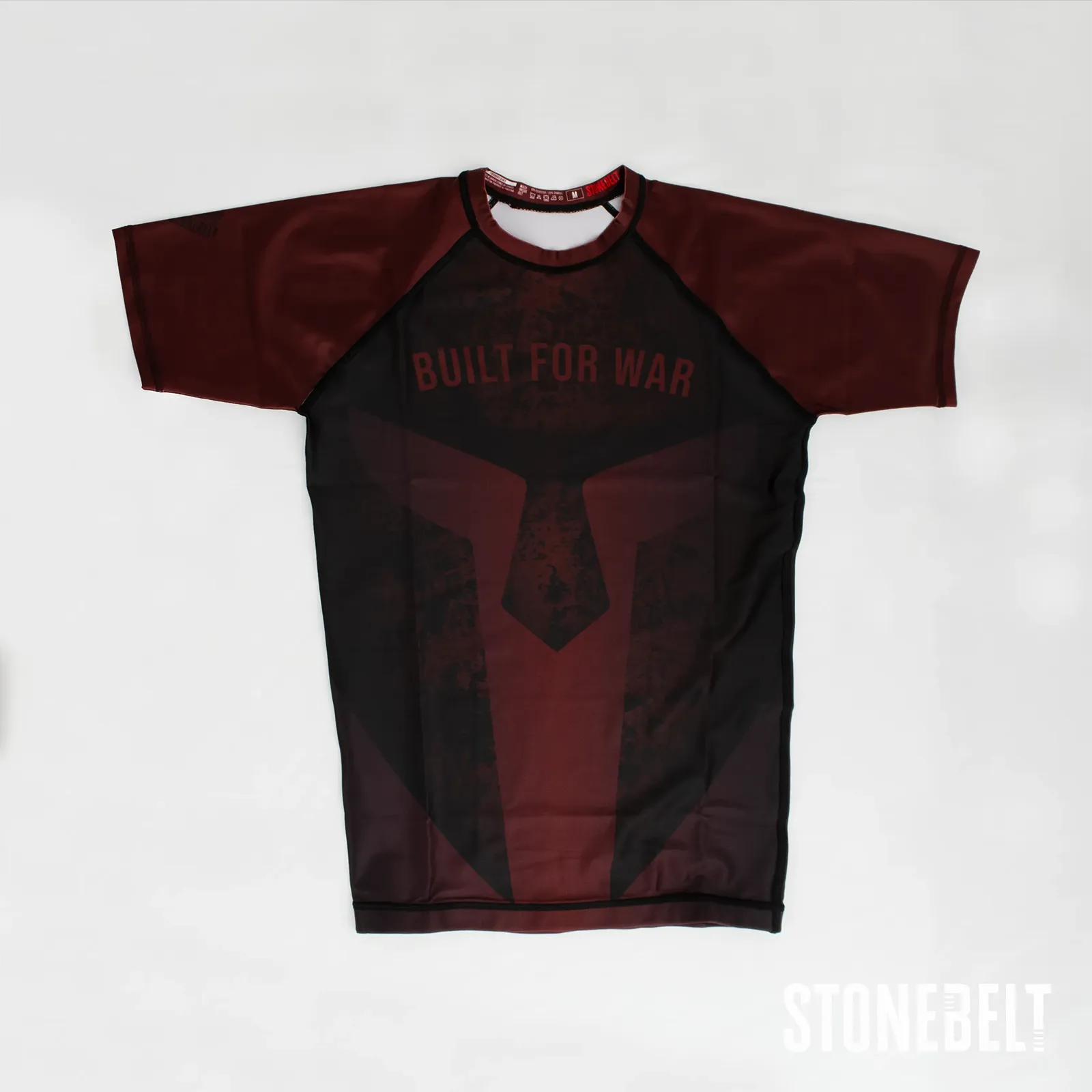Stonebelt Foundry short sleeve BJJ rashguard in red and black, flat front view with Built for War spartan graphic