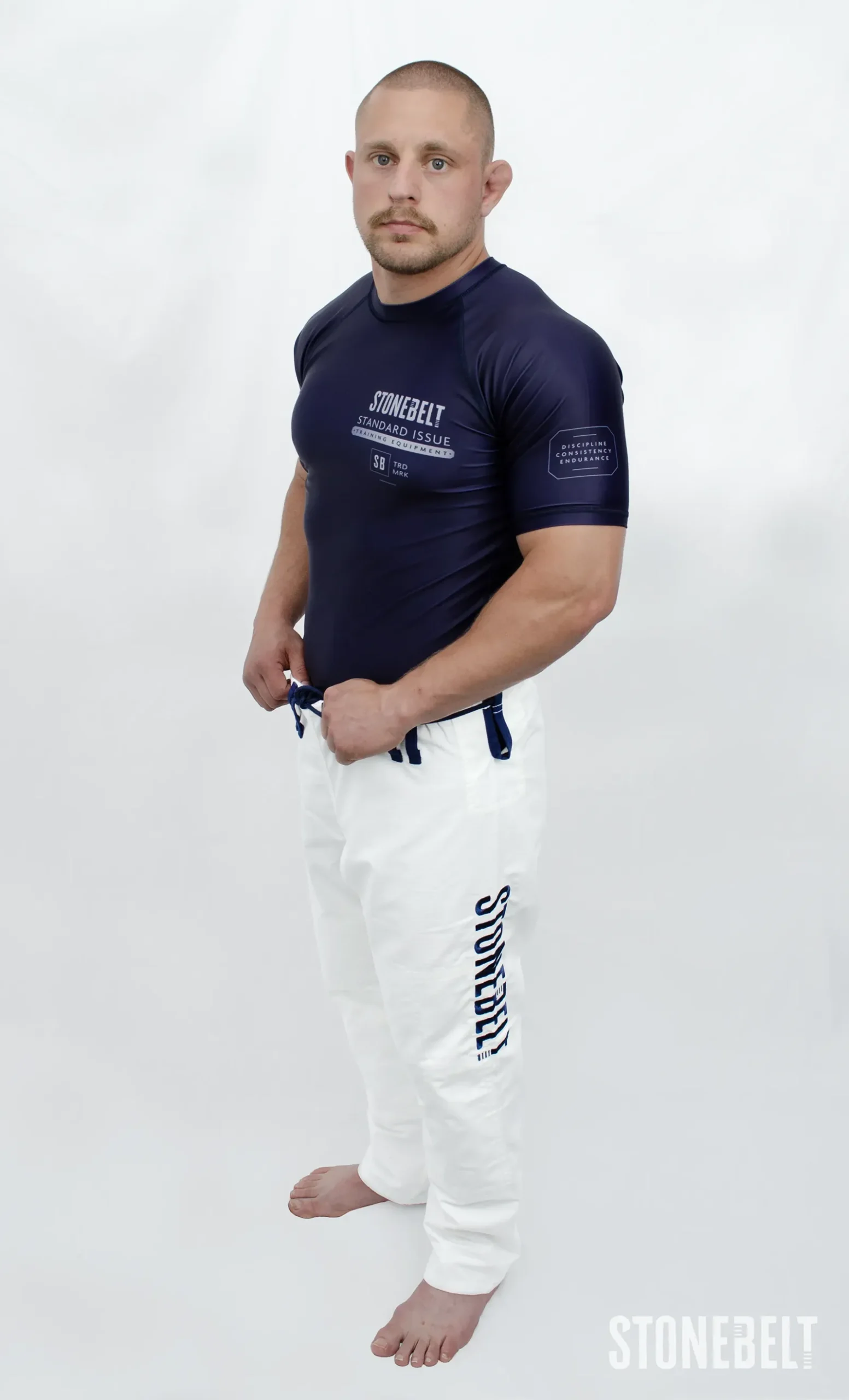 Model in Stonebelt Standard Issue navy rashguard and white Heritage gi pants, side view