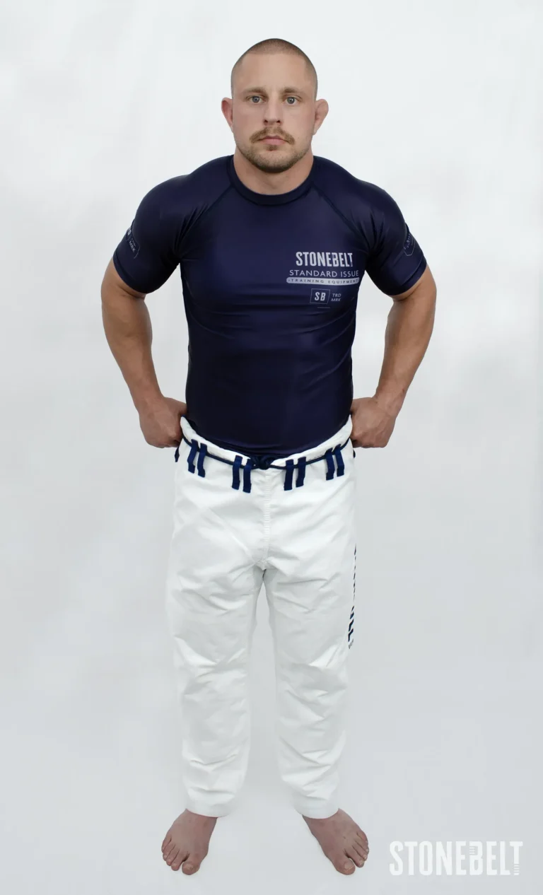 Model in Stonebelt Standard Issue navy rashguard and white Heritage gi pants, front view