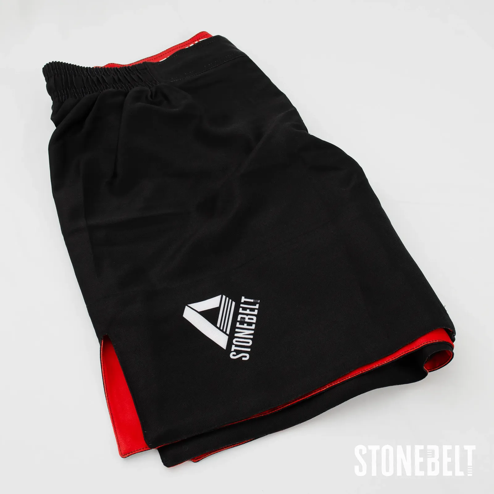 Stonebelt Heritage BJJ grappling shorts folded, showing leg logo, side slit, and red inner lining