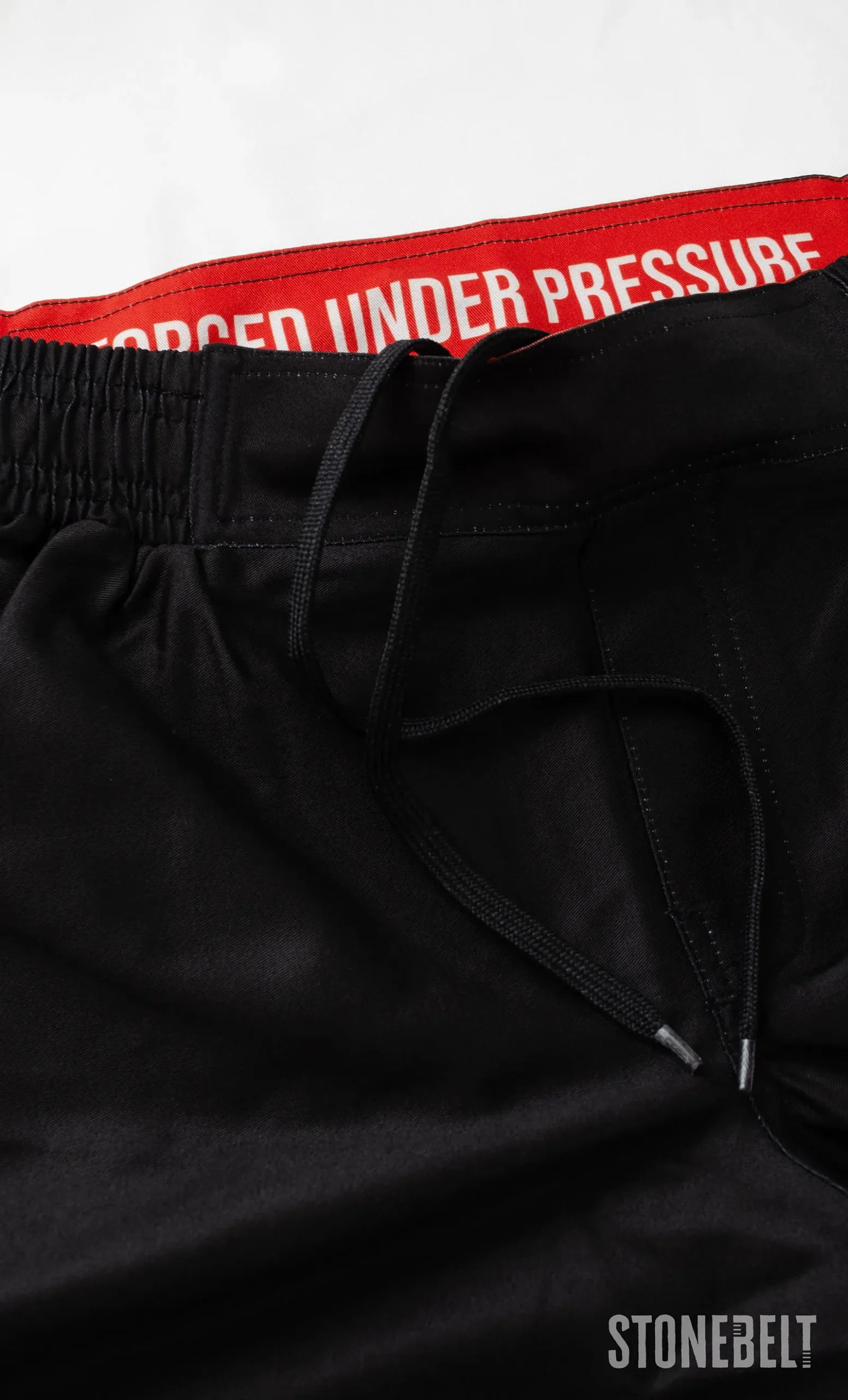 Close-up of Stonebelt Heritage grappling shorts waistband with red Forged Under Pressure print and black drawstring